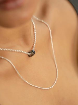 „Timeless sterling silver necklace, 48 cm length, adjustable to 46 cm and 44 cm, with two crystal donut pendants in onyx and smoky quartz; handcrafted from recycled materials, symbolizing grounding, clarity, and transformation.“