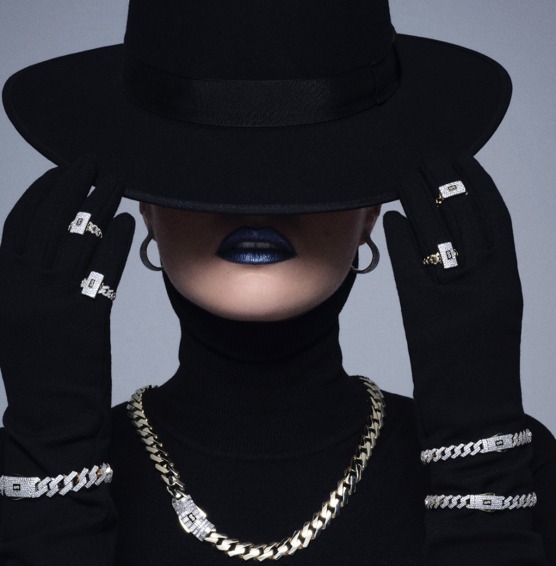 Woman in black hat showcasing Lesotho Jewellery with diamond rings, silver and pearl necklaces.